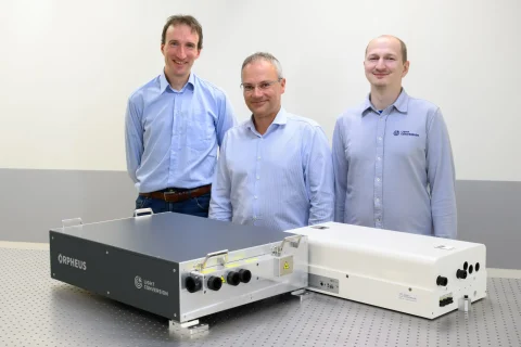 ORPHEUS product line developers next to a modern ORPHEUS-OPCPA and one of the first ORPHEUS OPAs.